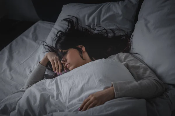 Mujer disgustada que tiene insomnio mientras está acostada en la cama por la noche - foto de stock