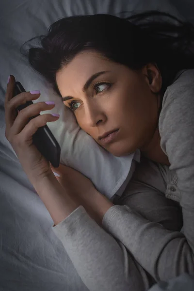 Awake woman with insomnia using smartphone in bedroom — Stock Photo