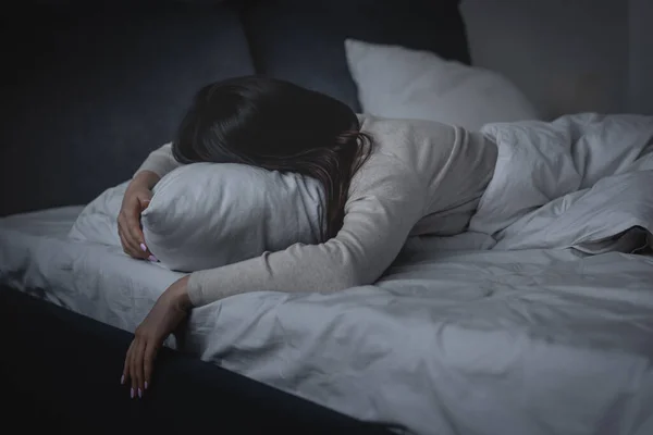 Mujer despierta con insomnio y acostada en la almohada por la noche - foto de stock