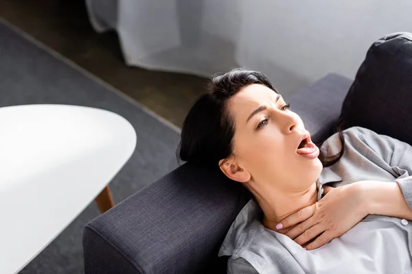 Больная женщина кашляет, лежа на диване — стоковое фото