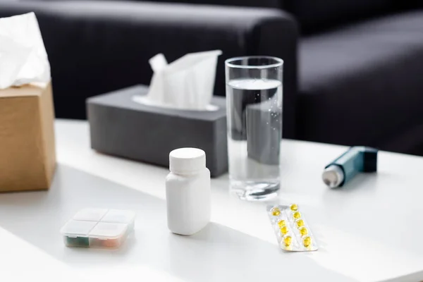 Foyer sélectif de verre d'eau près de la boîte de tissu, inhalateur et plaquette thermoformée avec des pilules — Photo de stock