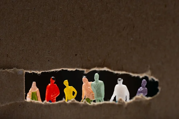 Selective focus of cardboard with hole and people figures isolated on black, concept of social equality — Stock Photo