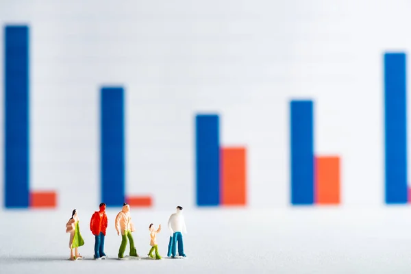 Selective focus of people figures on white surface with graphs at background, concept of equality — Stock Photo