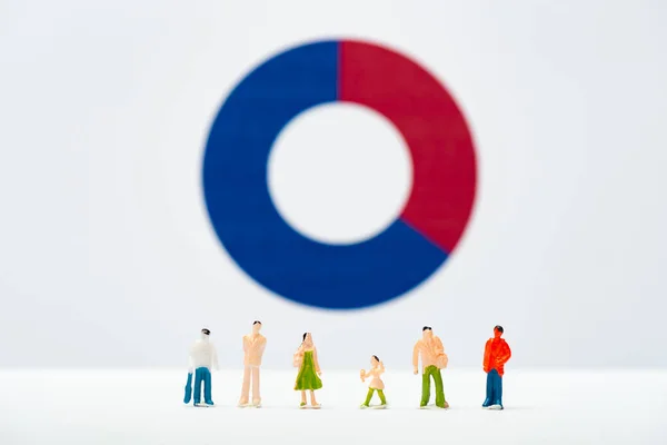 Selective focus of row of people figures on white surface with diagram at background, concept of inequality — Stock Photo