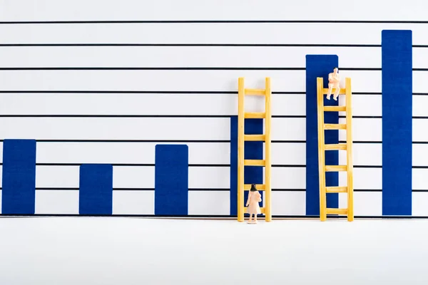 Personas figuras con escaleras cerca de gráficos en la superficie blanca, concepto de igualdad - foto de stock