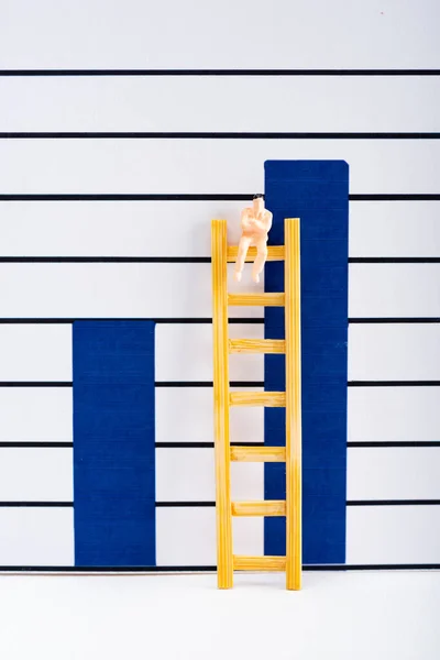 Muñeca en escalera sobre superficie blanca cerca de gráficos en el fondo, concepto de igualdad - foto de stock