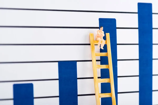 Personaje de muñeca en escalera cerca de gráficos azules en segundo plano, concepto de igualdad - foto de stock