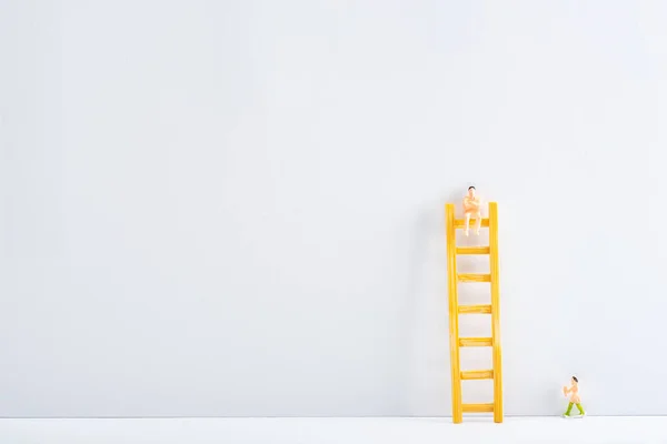 Dos personas figuras con escalera sobre superficie blanca sobre fondo gris, concepto de igualdad de derechos - foto de stock