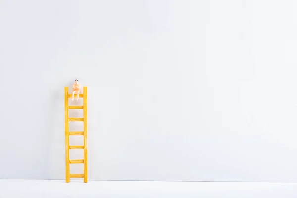 Muñeca en escalera sobre superficie blanca sobre fondo gris, concepto de igualdad de derechos - foto de stock