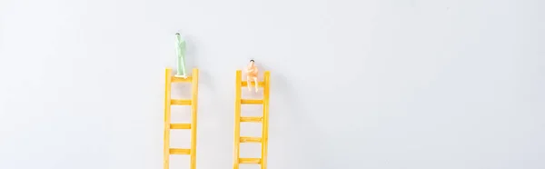 Панорамний знімок двох людей фігури на драбинах на білому тлі, концепція прав рівності — стокове фото