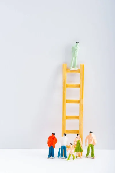 Muñeca en escalera con figuras de personas en superficie blanca sobre fondo gris, concepto de derechos de igualdad - foto de stock