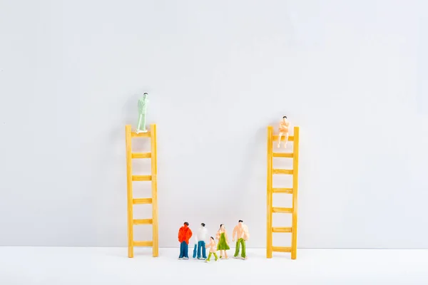 Muñecas en escaleras con figuras de personas en superficie blanca sobre fondo gris, concepto de derechos de igualdad - foto de stock