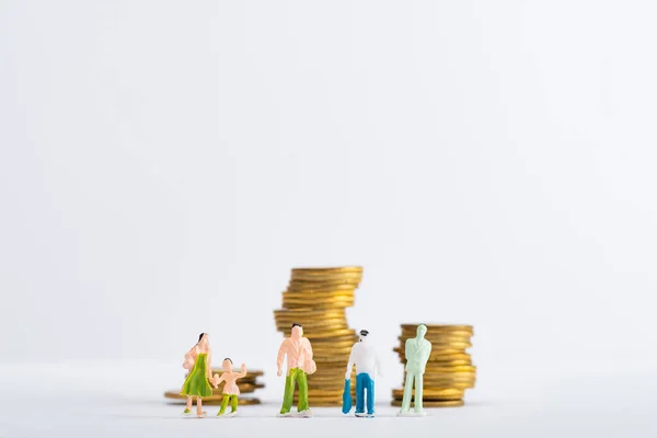 Concept of financial equality with people figures with stacked golden coins on white surface isolated on white — Stock Photo