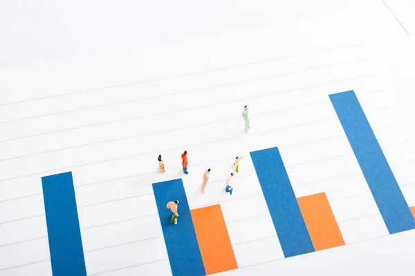 Vista de ángulo alto de figuras de personas de juguete en la superficie de gráficos aislados en blanco, concepto de igualdad - foto de stock