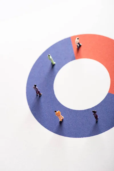 Vista de ángulo alto de las figuras de la gente en el diagrama redondo rojo y azul en la superficie blanca, concepto de disparidad - foto de stock