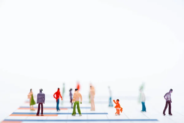 Close up view of plastic people figures on surface with graphs isolated on white, equality concept — Stock Photo