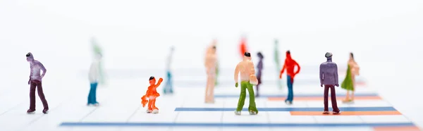 Concept of equality with plastic people figures on surface with graphs isolated on white, panoramic shot — Stock Photo