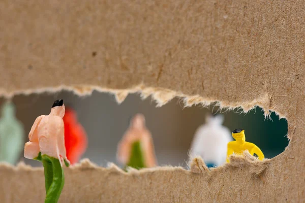 Selective focus of people figures near hole in cardboard with silhouettes of toys at background — Stock Photo
