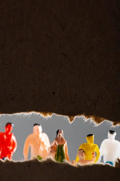 Foco seletivo de figuras de pessoas perto de buraco em papelão isolado em cinza, conceito de direitos sociais — Fotografia de Stock