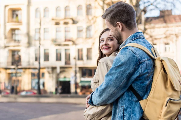 Mädchen und Mann umarmen sich, lächeln und schauen einander in der Stadt an — Stockfoto
