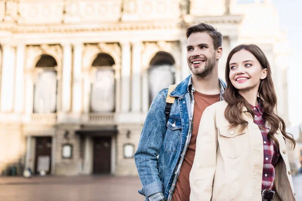 Felice fidanzato e fidanzata guardando altrove e sorridendo in città — Foto stock