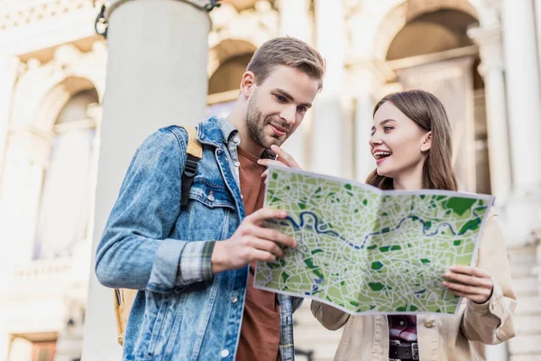 Low angle view of thoughtful boyfriend and happy girlfriend with map in city — Stock Photo