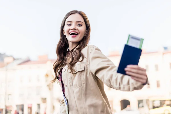 Низкий угол зрения взволнованной красивой женщины с паспортом с авиабилетом — стоковое фото
