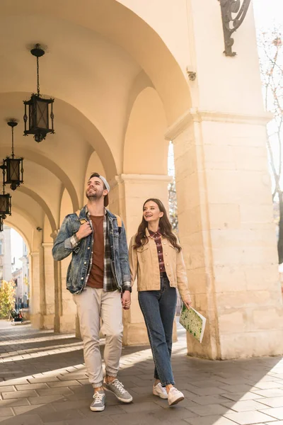 Boyfriend and girlfriend with map walking together in city — Stock Photo