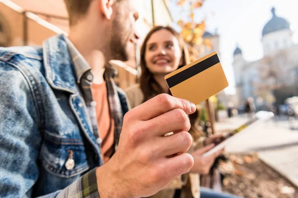 Cropped view of man with girl looking at each other, smiling and showing credit card — Stock Photo