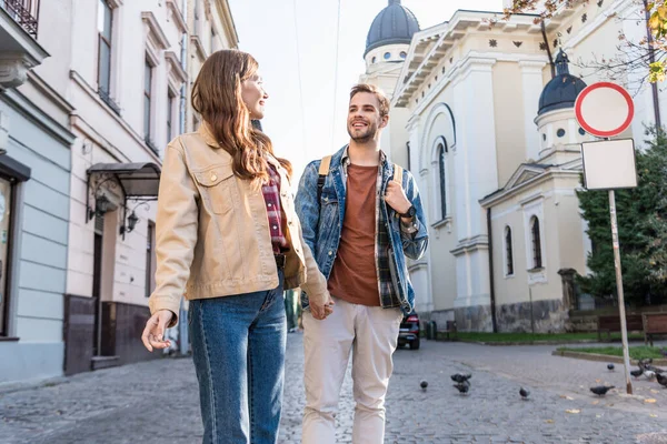 Enfoque selectivo de pareja mirándose y tomándose de la mano en la ciudad - foto de stock