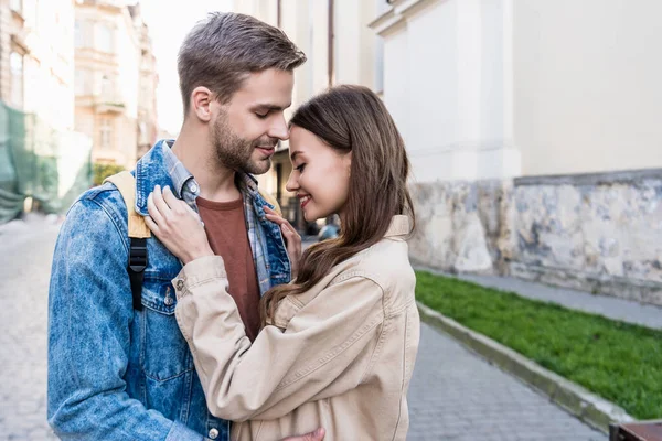 Enfoque selectivo de pareja abrazándose y sonriendo en la ciudad - foto de stock