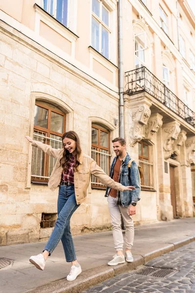 Couple having fun while walking on sidewalk in city — Stock Photo