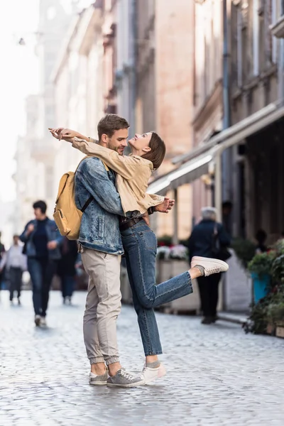 Boyfriend and girlfriend with raising leg hugging in city — Stock Photo