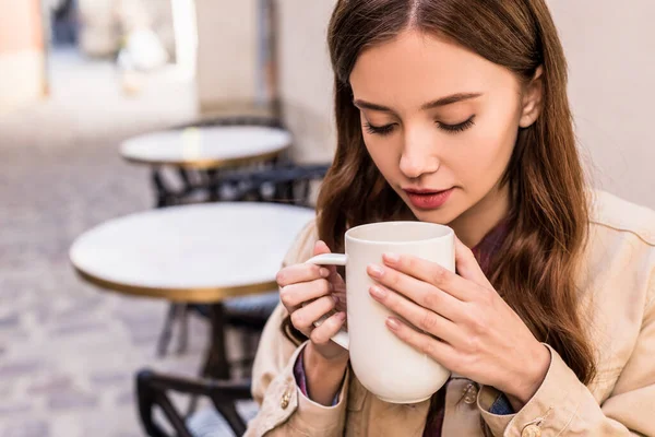 Enfoque selectivo de la mujer sosteniendo la taza de té en la cafetería - foto de stock