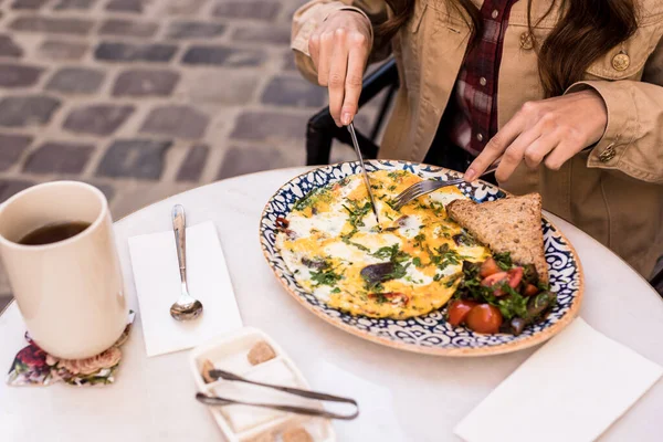 Vista ritagliata della donna che mangia frittata nel caffè — Foto stock