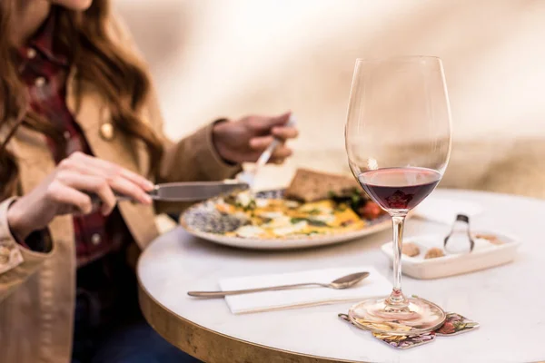 Vista parcial de la mujer comiendo con copa de vino en la cafetería - foto de stock