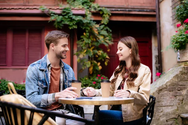 Selective focus of couple with disposable cups of coffee in cafe in city — Stock Photo