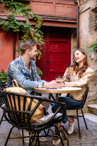 Selective focus of couple with paper cups of coffee looking at each other in cafe in Lviv — Stock Photo