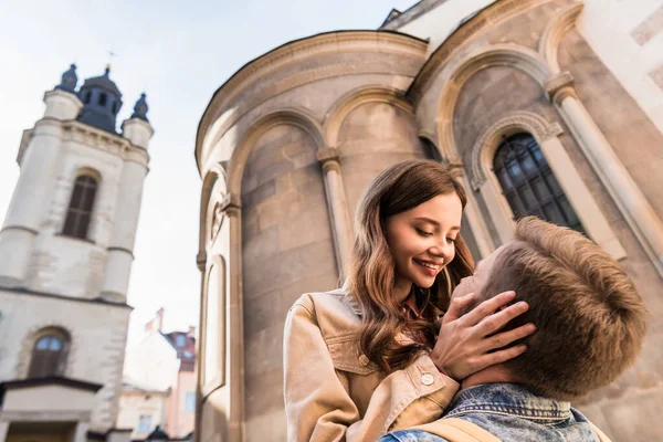 Low angle view of girlfriend touching male face near buildings in city — Stock Photo