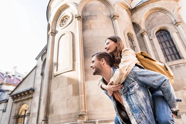 Low angle view of man piggybacking girlfriend near building in city — Stock Photo
