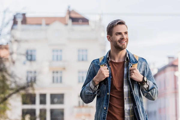 Schöner Mann mit Rucksack lächelt in der Stadt — Stockfoto