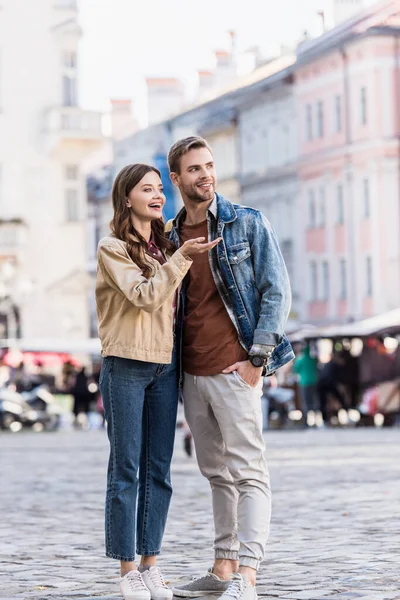 Novio y novia mirando hacia otro lado y sonriendo en la ciudad - foto de stock