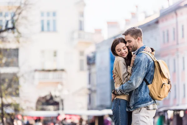 Novio y novia abrazándose con los ojos cerrados y sonriendo en la ciudad - foto de stock