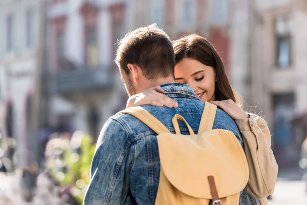 Fidanzata abbracciare fidanzato con beige zaino in città — Foto stock