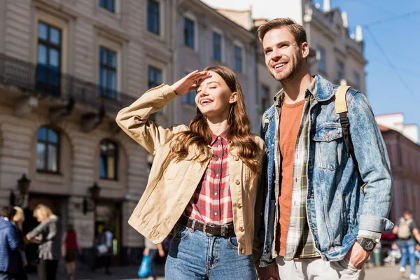 Freundin verdeckt Gesicht vor Sonnenlicht und Freund lächelt in der Stadt — Stockfoto