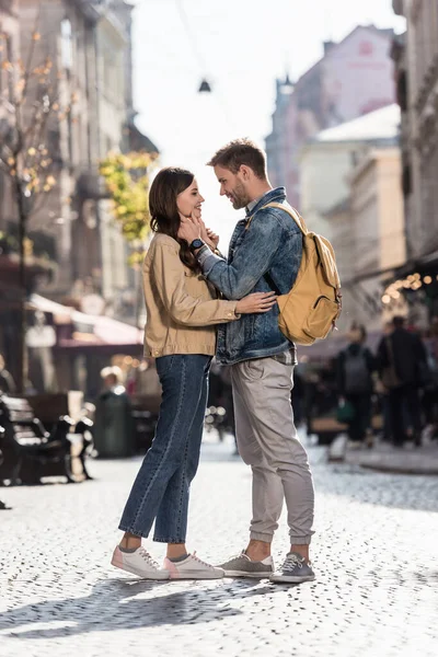 Namorado e namorada olhando um para o outro sorrindo e abraçando na cidade na Europa — Fotografia de Stock