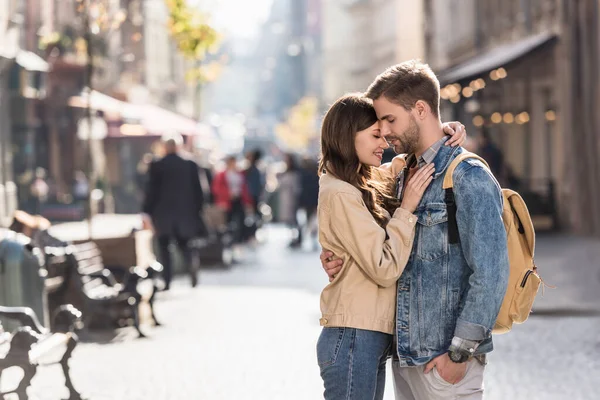 Boyfriend with hand in pocket and girlfriend hugging with closed eyes in city in Europe — Stock Photo