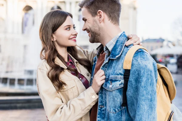 Woman and man hugging, smiling and looking at each other in city — Stock Photo