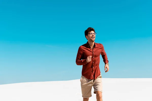 Happy man running on sandy beach against clear blue sky — Stock Photo