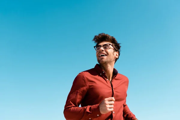 Low angle view of happy man running against clear blue sky — Stock Photo